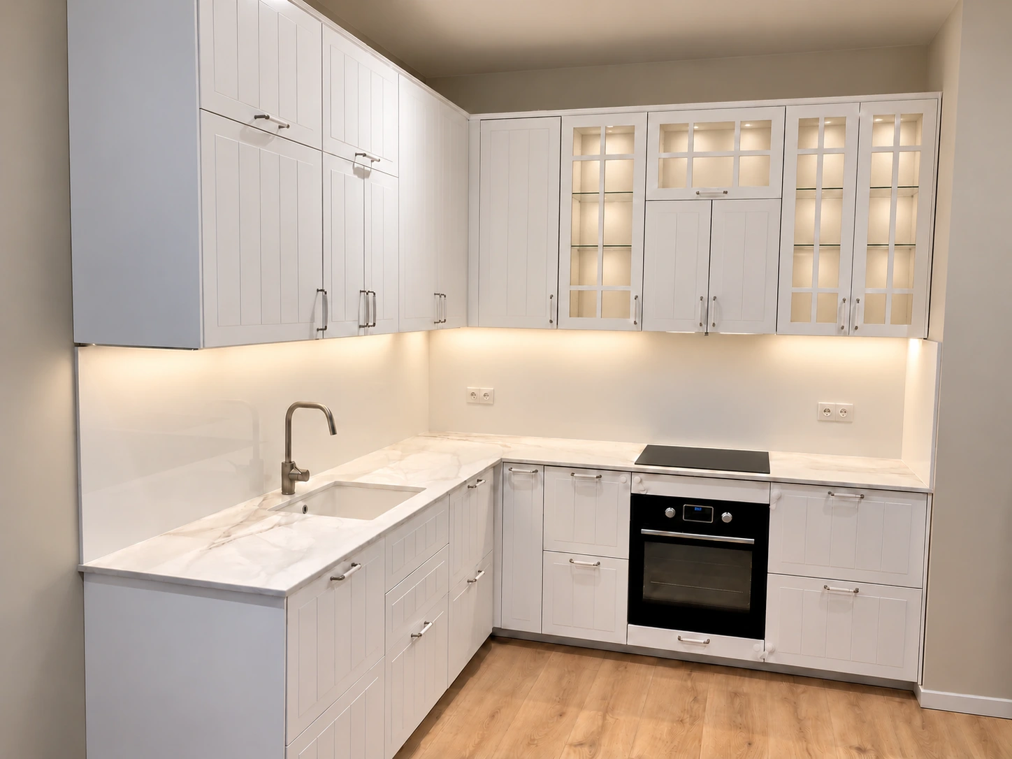 Witte hoekkeuken in Amsterdam met glazen kastdeuren en verlichting onder de bovenkasten